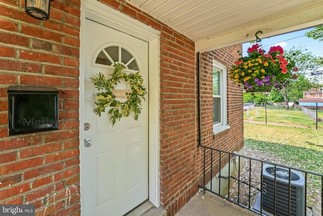 615 Jansen Ave, Essington, PA 19029 - property entrance featuring cooling unit, a porch, brick siding, and fence