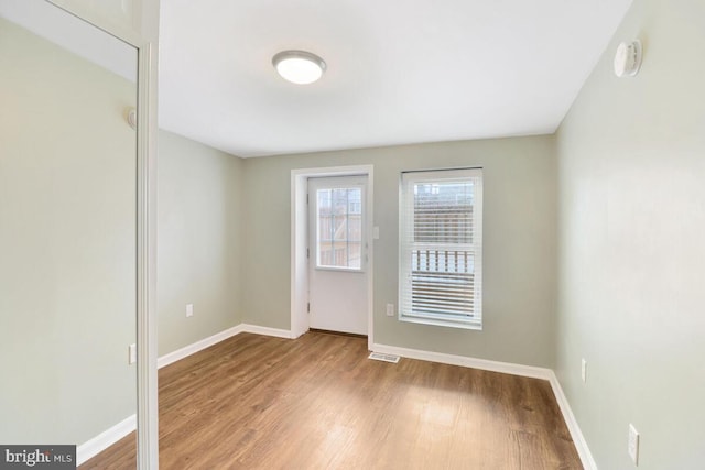 empty room with wood finished floors, baseboards, and a smoke detector