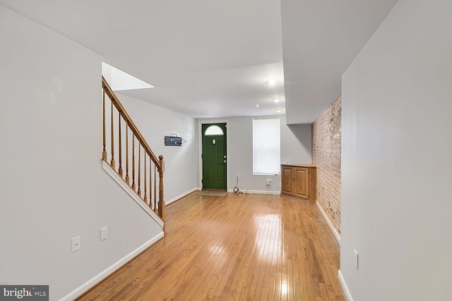 entryway featuring light wood finished floors, stairway, and baseboards