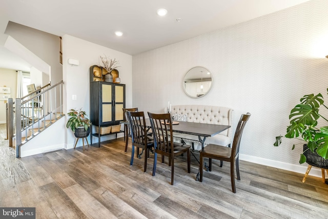 dining area featuring baseboards, wood finished floors, wallpapered walls, stairs, and recessed lighting