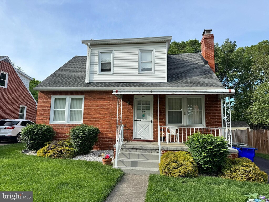 bungalow-style home featuring brick siding, roof with shingles, a chimney, and a porch