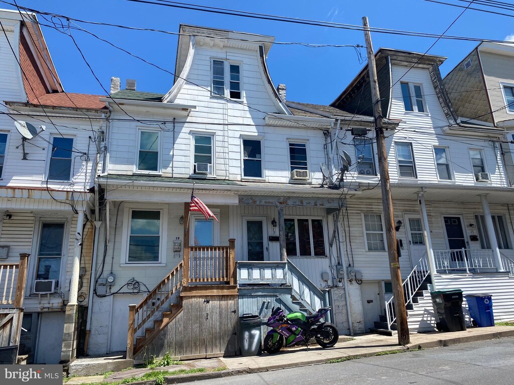 multi unit property with a porch, stairway, and a chimney