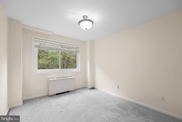 carpeted empty room featuring baseboards and radiator