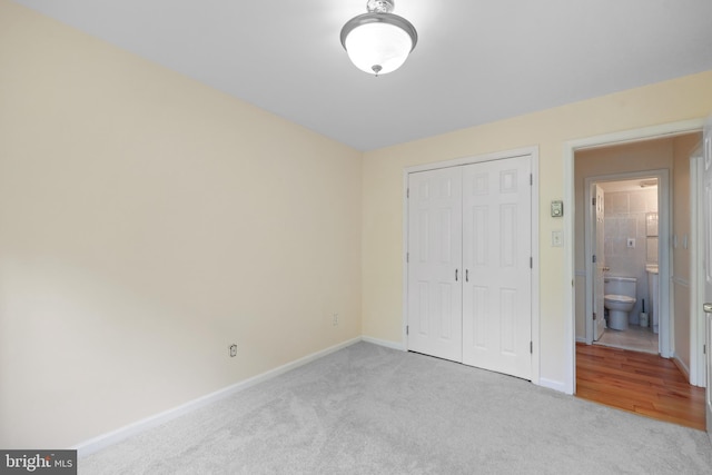 unfurnished bedroom with carpet, a closet, and baseboards