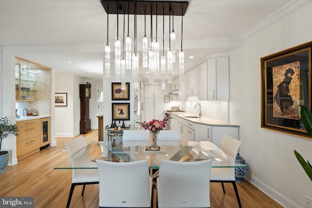 700 New Hampshire Ave NW Unit 507, Washington, DC 20037 - dining area with wine cooler, baseboards, light wood-style floors, and crown molding