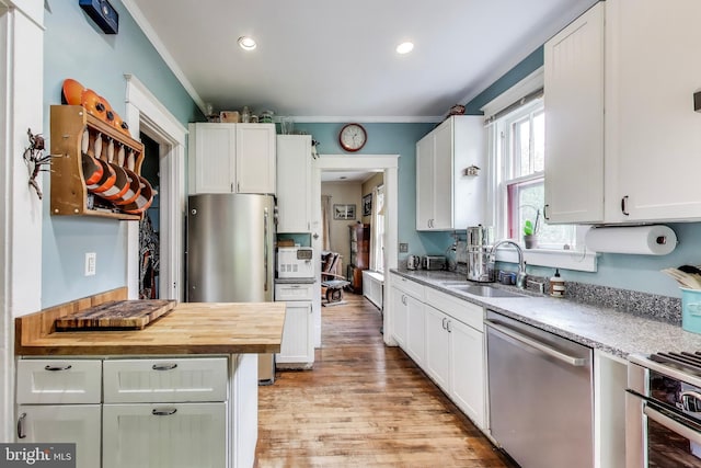 7017 Woodland Ave, Takoma Park, MD 20912 - kitchen featuring appliances with stainless steel finishes, a sink, ornamental molding, wooden counters, and light wood-style floors