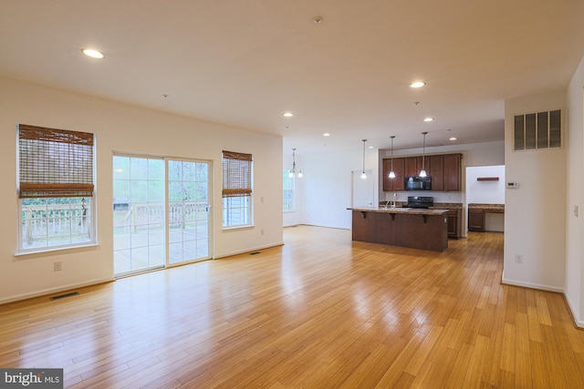 596 Claiborne Road, North East, MD 21901 - kitchen with black microwave, open floor plan, a kitchen breakfast bar, stove, and light wood-style flooring