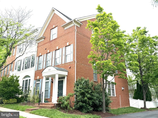 view of front of home featuring brick siding and fence