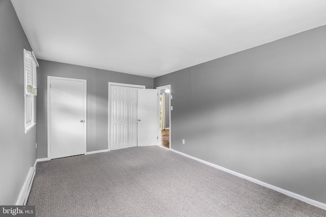 unfurnished bedroom with two closets, baseboards, and carpet floors