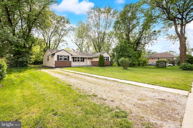 ranch-style house featuring brick siding, a front yard, and driveway