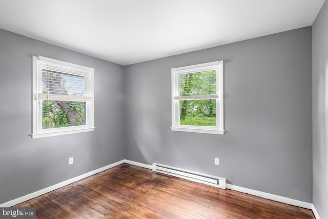 unfurnished room with a baseboard heating unit, baseboards, and dark wood-style flooring