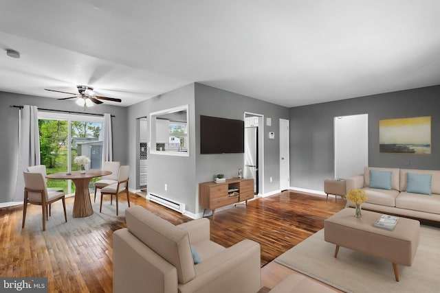 living room featuring a baseboard heating unit, wood finished floors, baseboards, and a ceiling fan