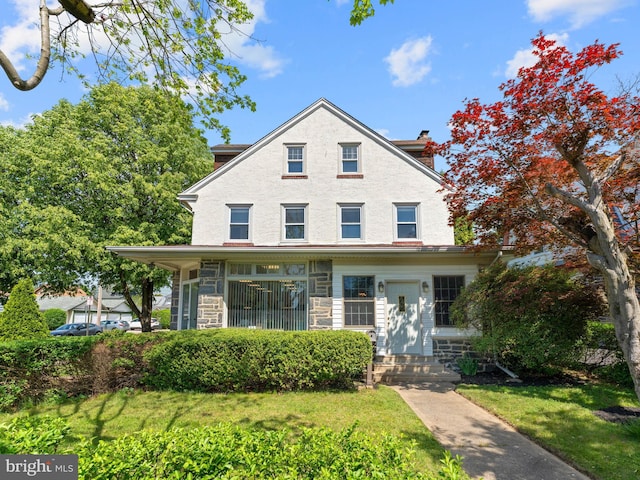 view of front of house featuring stone siding, a front yard, and a chimney