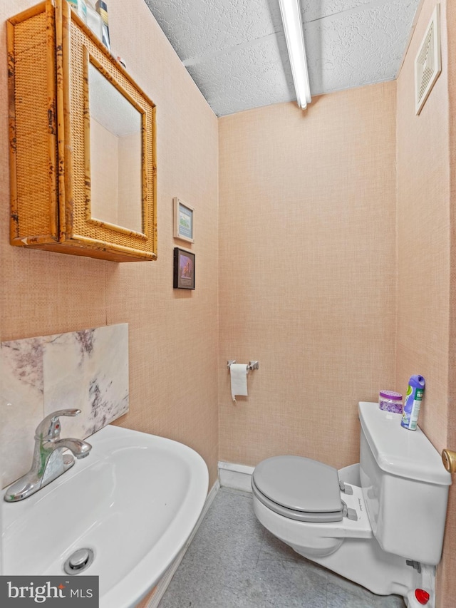 bathroom featuring a sink, toilet, a textured ceiling, and tile patterned floors