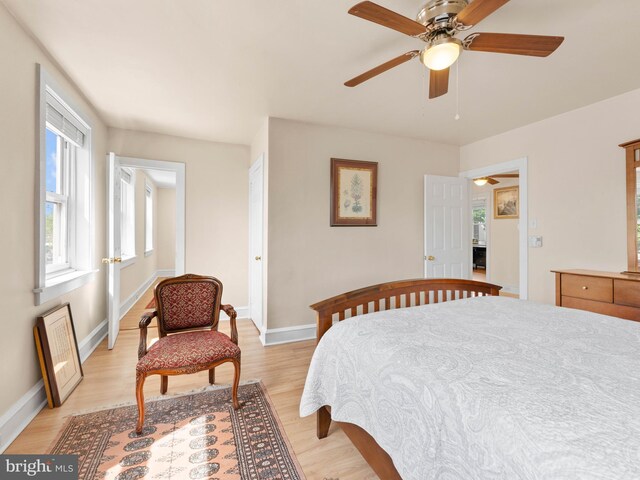 bedroom with light wood-type flooring, baseboards, and multiple windows