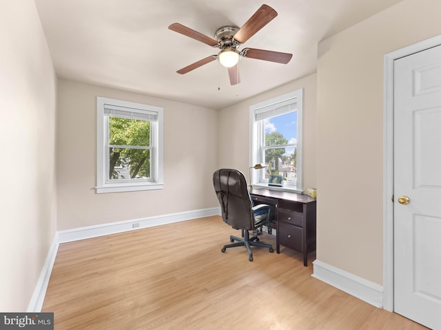 home office featuring healthy amount of natural light, wood finished floors, a ceiling fan, and baseboards