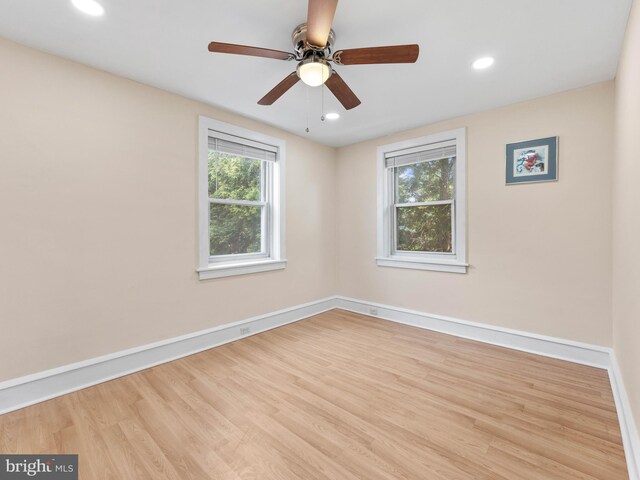 empty room featuring healthy amount of natural light, baseboards, wood finished floors, and recessed lighting