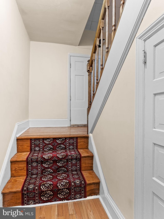 stairway with wood finished floors and baseboards