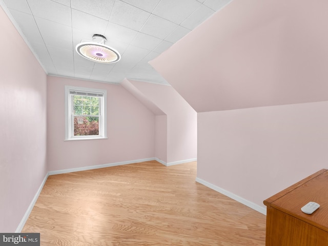 additional living space featuring light wood-style flooring, lofted ceiling, and baseboards