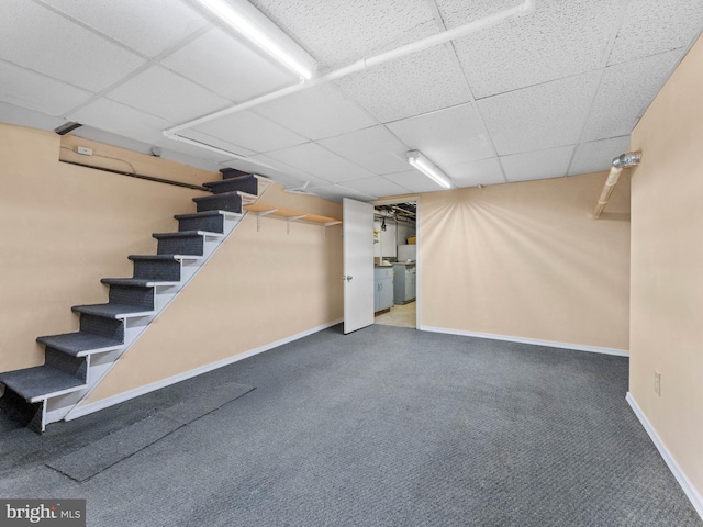 finished basement with carpet floors, stairway, a drop ceiling, and baseboards