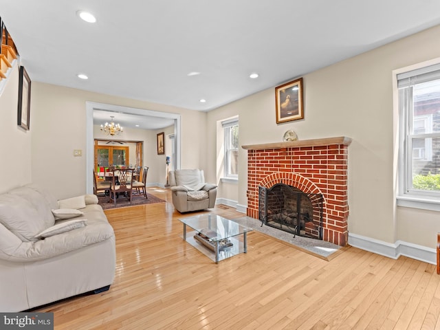 living room with a brick fireplace, healthy amount of natural light, hardwood / wood-style flooring, a chandelier, and recessed lighting