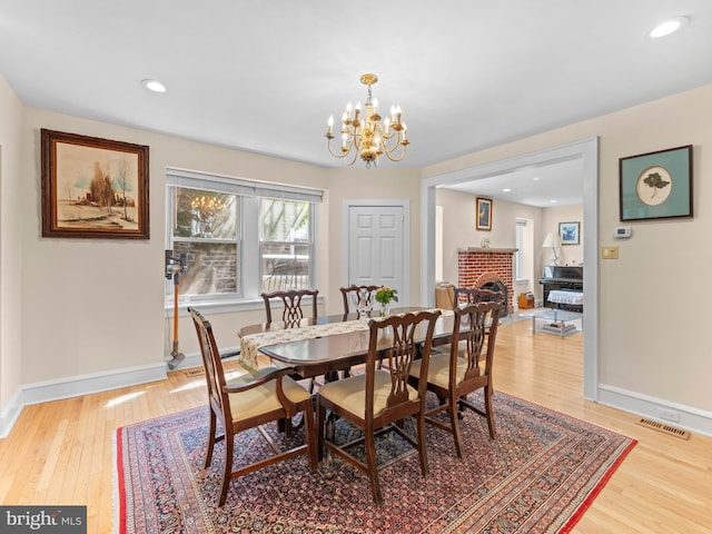 dining room featuring a chandelier, light wood-style floors, baseboards, a fireplace, and recessed lighting