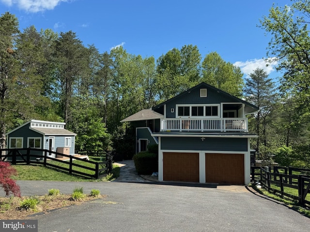 view of front of home with a balcony, fence, a garage, and asphalt driveway