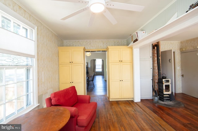 116 Oakley St, Cambridge, MD 21613 - sitting room with wallpapered walls, dark wood finished floors, a wood stove, arched walkways, and crown molding