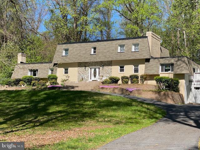 view of front of home featuring mansard roof, a shingled roof, and a front yard