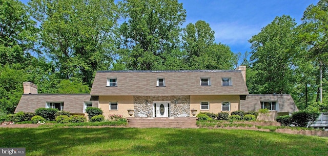 view of front of house featuring a front lawn, a chimney, and stone siding
