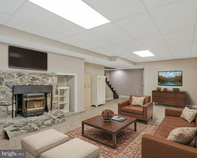 living area with a drop ceiling, stairs, and baseboards