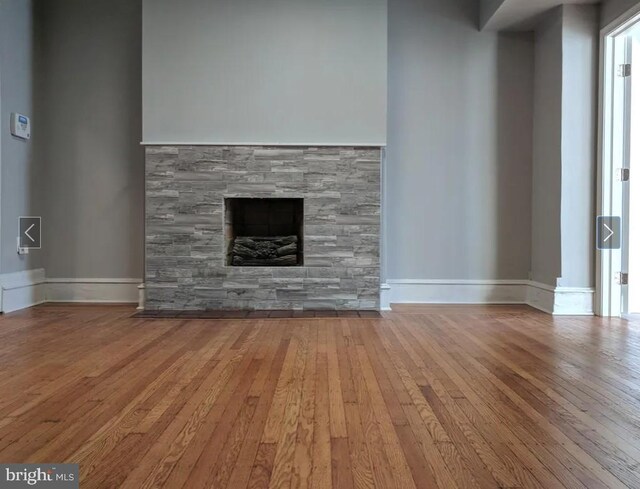 137 S 49th St, Philadelphia, PA 19139 - unfurnished living room featuring hardwood / wood-style flooring, a stone fireplace, and baseboards
