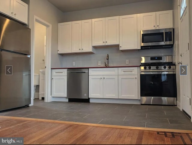 137 S 49th St, Philadelphia, PA 19139 - kitchen featuring appliances with stainless steel finishes, dark wood finished floors, white cabinetry, decorative backsplash, and a sink