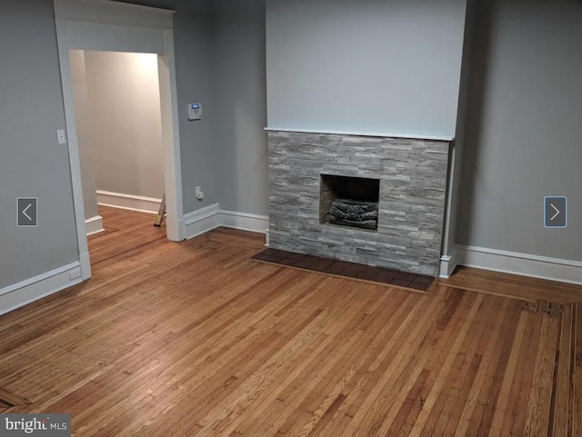 137 S 49th St, Philadelphia, PA 19139 - unfurnished living room with baseboards, a stone fireplace, and wood finished floors