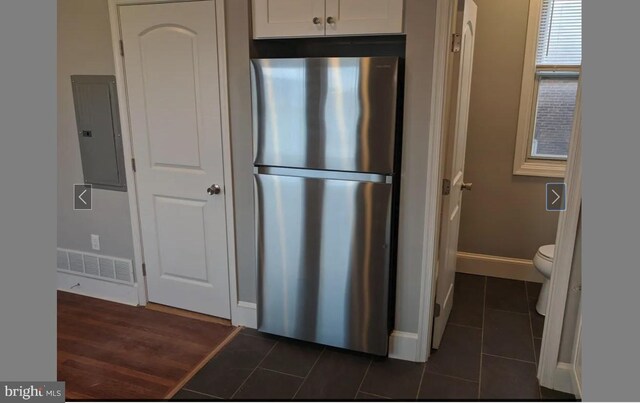 137 S 49th St, Philadelphia, PA 19139 - kitchen with freestanding refrigerator, electric panel, dark tile patterned floors, white cabinetry, and baseboards
