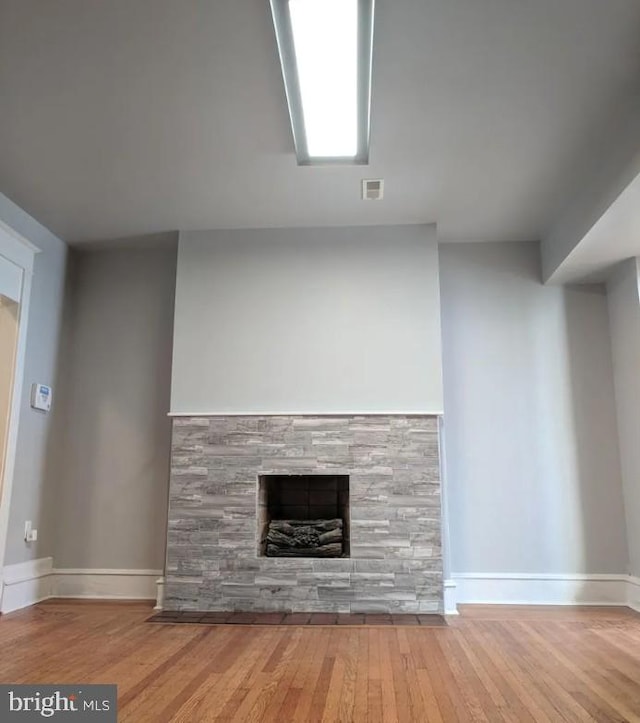 137 S 49th St, Philadelphia, PA 19139 - unfurnished living room featuring baseboards, hardwood / wood-style floors, and a stone fireplace