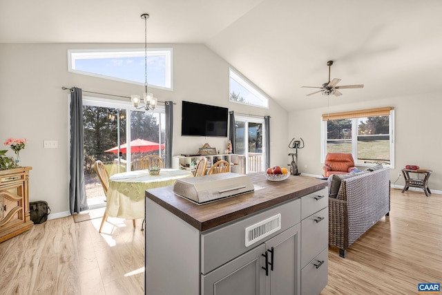 kitchen featuring butcher block countertops, ceiling fan with notable chandelier, visible vents, light wood-style flooring, and open floor plan