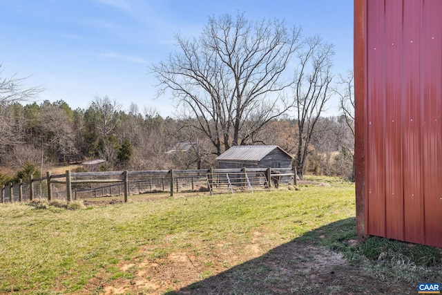 view of yard with fence, an outbuilding, an outdoor structure, and a view of trees