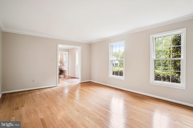 empty room featuring baseboards, crown molding, and light wood-style flooring