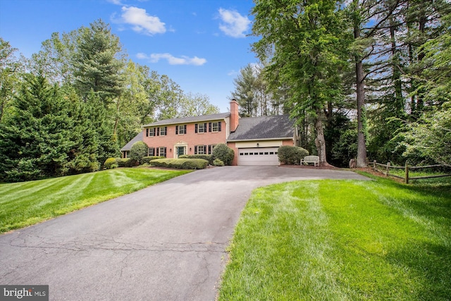 colonial-style house featuring driveway, a chimney, and an attached garage