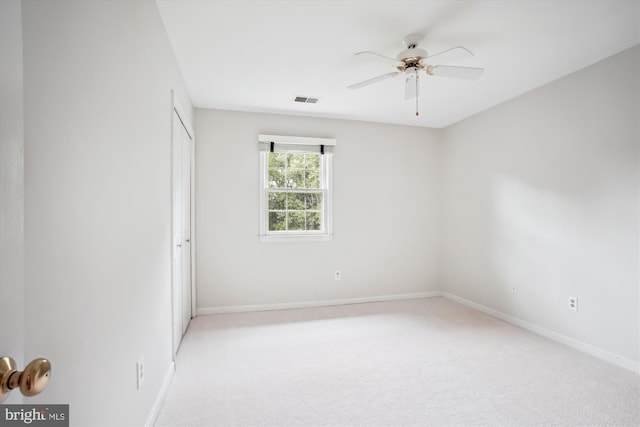 empty room with a ceiling fan, baseboards, and light carpet