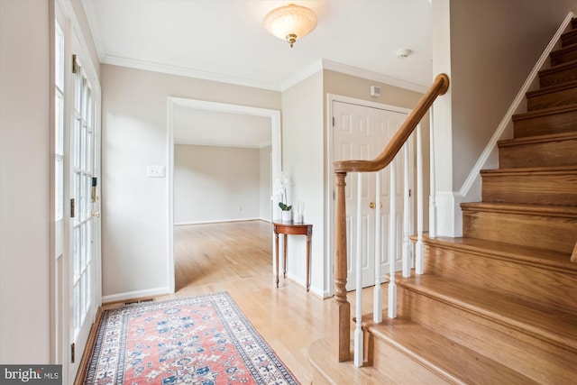 foyer featuring stairway, light wood finished floors, baseboards, and crown molding