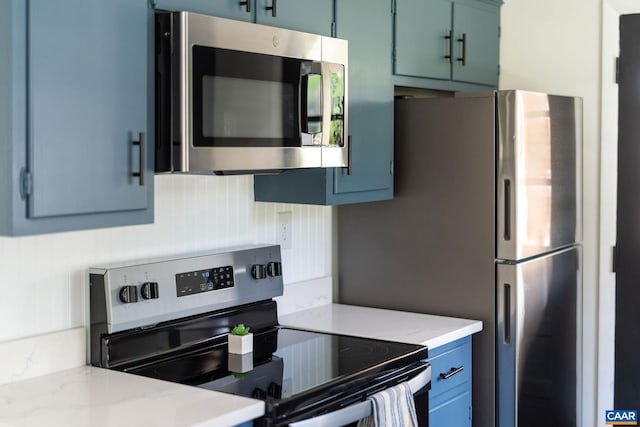 kitchen featuring blue cabinets, appliances with stainless steel finishes, and light stone countertops