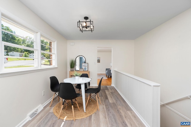 dining space with baseboards, a notable chandelier, light wood finished floors, and visible vents