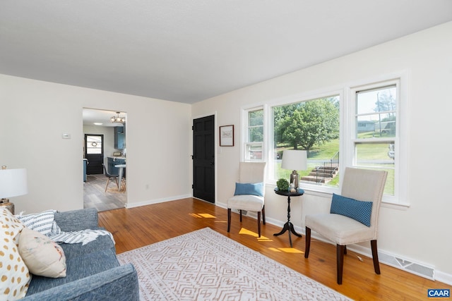 living room with a chandelier, visible vents, wood finished floors, and baseboards