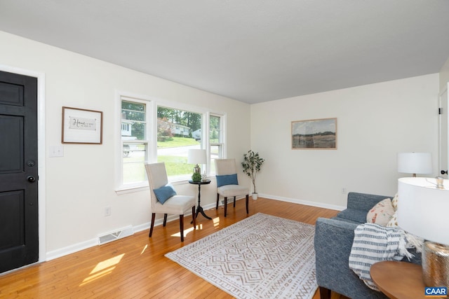 sitting room featuring baseboards, visible vents, and light wood-style floors