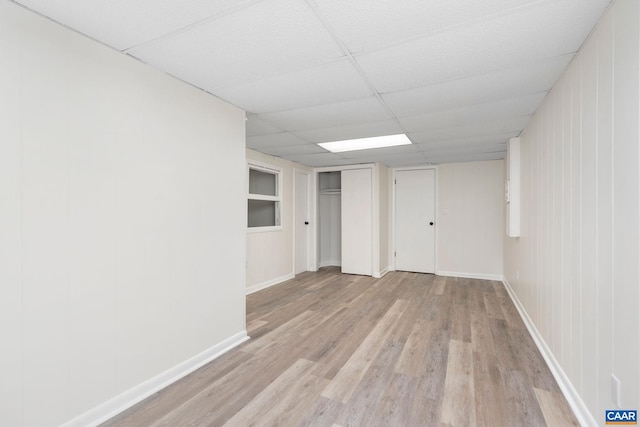 finished basement featuring baseboards, a paneled ceiling, and wood finished floors