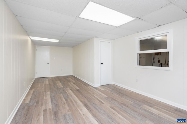spare room with a paneled ceiling, baseboards, and wood finished floors