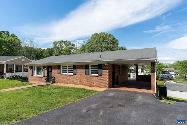 ranch-style home featuring brick siding, driveway, a front yard, a carport, and a shingled roof
