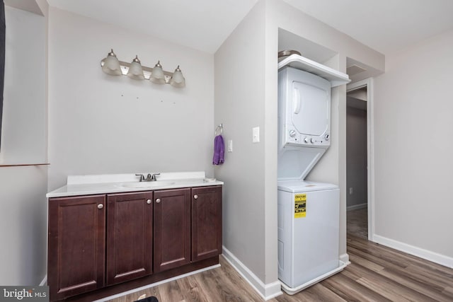 2108 E Hoffman St, Baltimore, MD 21213 - washroom featuring wood finished floors, baseboards, a sink, and stacked washer and dryer